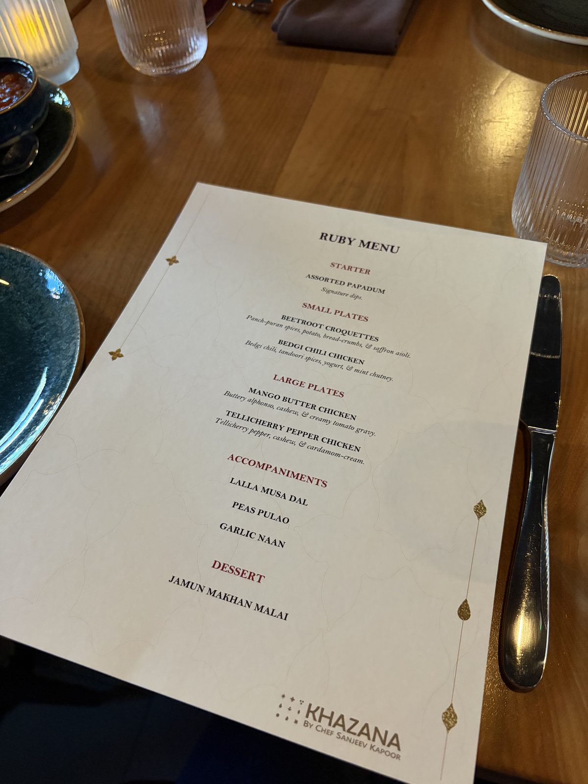A printed dinner menu at a place setting on a wooden table