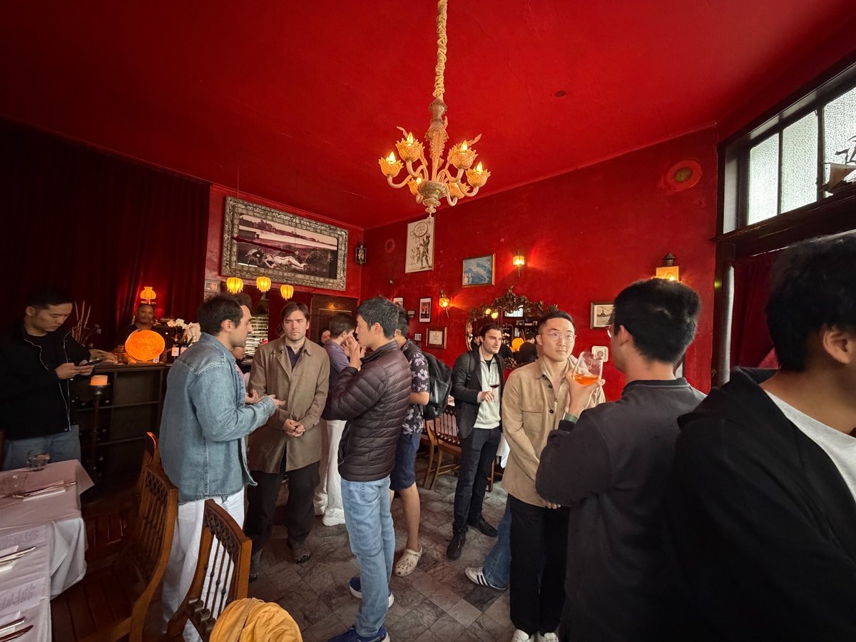 Guests talking under a chandelier in a red dining room